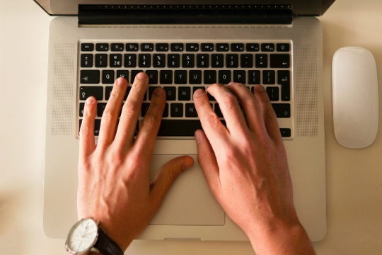 Aeriel view of male hands on a Mac keyboard