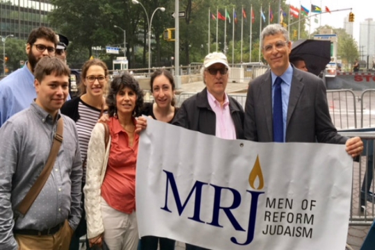 Group of individuals standing behind a Men of Reform Judaism sign held by Rabbi Rick Jacobs