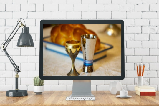 Home office setup with a Shabbat scene displayed on screen