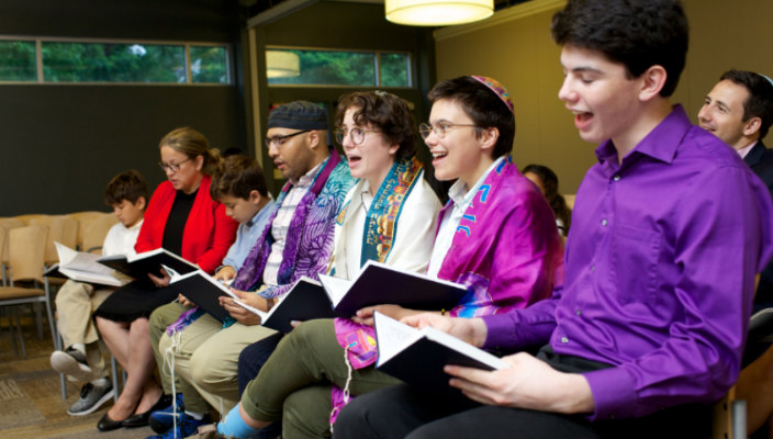 Group of teens and adults facing forward sitting in pews