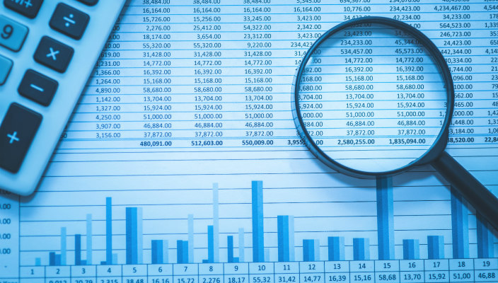 Graphic displaying a flatlay of budget spreasheets and a calculator