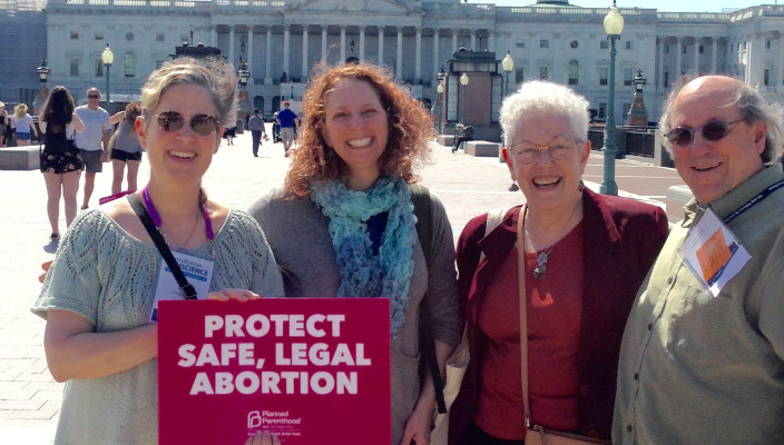 Four individuals holding a sign that says PROTECT SAFE LEGAL ABORTION