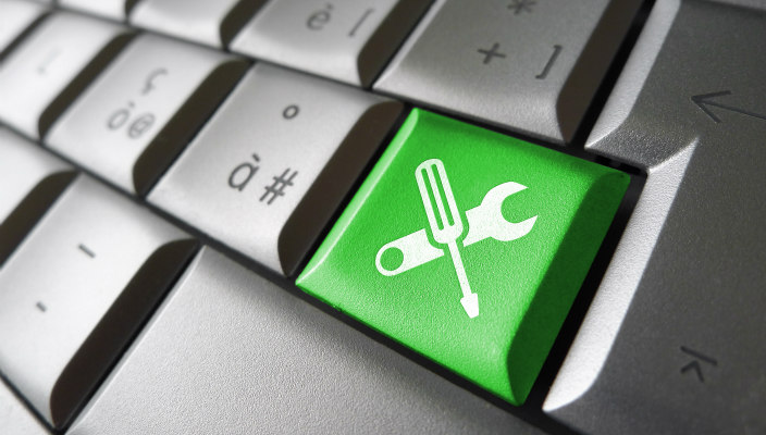 Computer keyboard with a green key that has a wrench and screwdriver on it